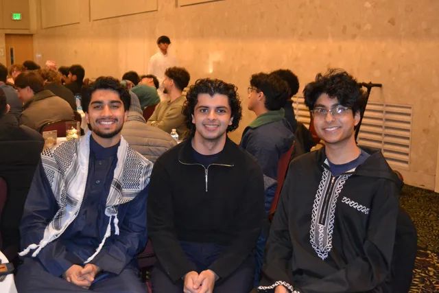 Three students smiling together in their seats