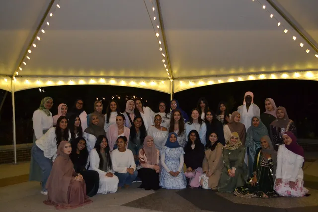 A group photo at Sisters’ Banquet beneath a tent and string lights