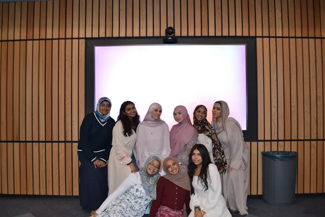 A group posing in front of a classroom screen