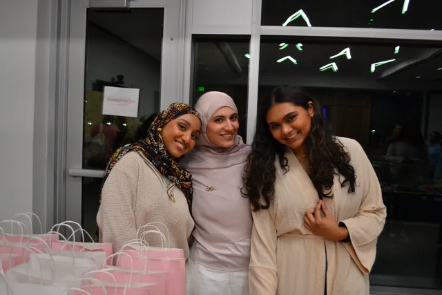 Three attendees beside pink gift bags