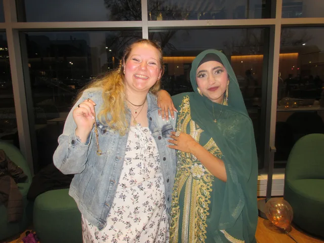 Two attendees smiling together by a window
