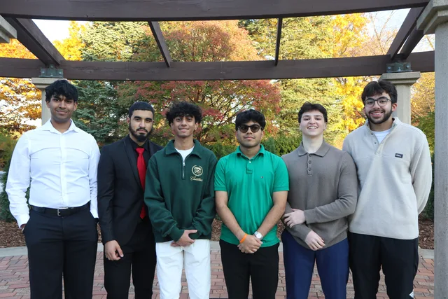 Six students together beneath a garden pergola